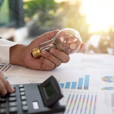 Hand of businessman hold light bulb with coin. Concept of Cost reduction and Reduce energy Hand of businessman hold light bulb with coin. Concept of Cost reduction and Reduce energy